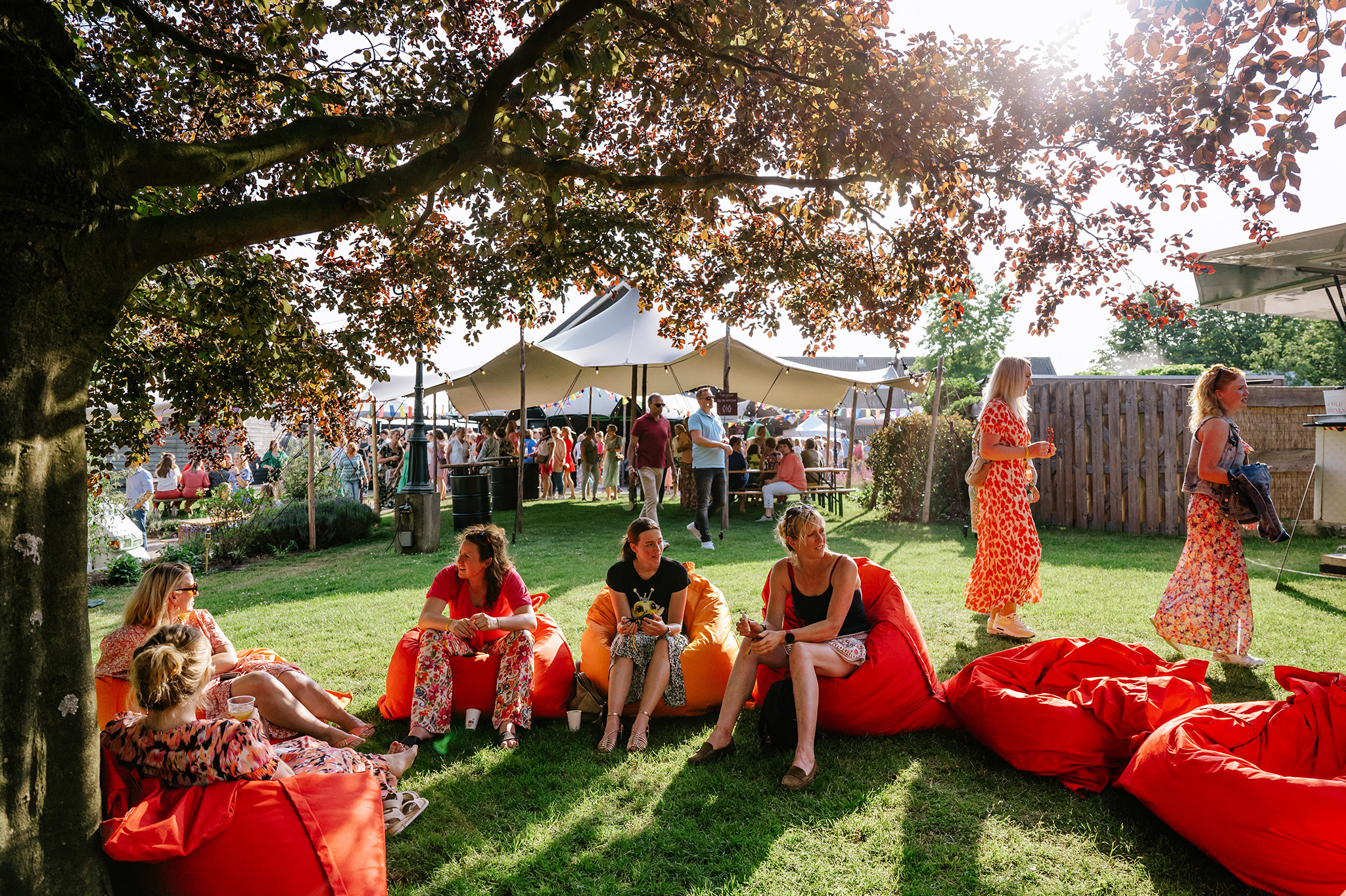 Ontspannen gasten genieten van de sfeer, zittend op comfortabele zitzakken in de tuin van De Schildhoeve Buitengewoon