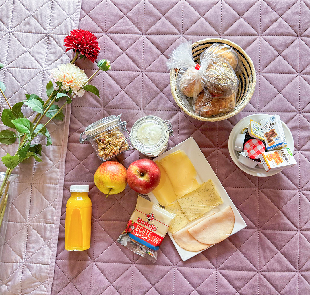 Afbeelding van een smakelijk ontbijt geserveerd op een tafel, met vers fruit, broodjes, croissants en sap